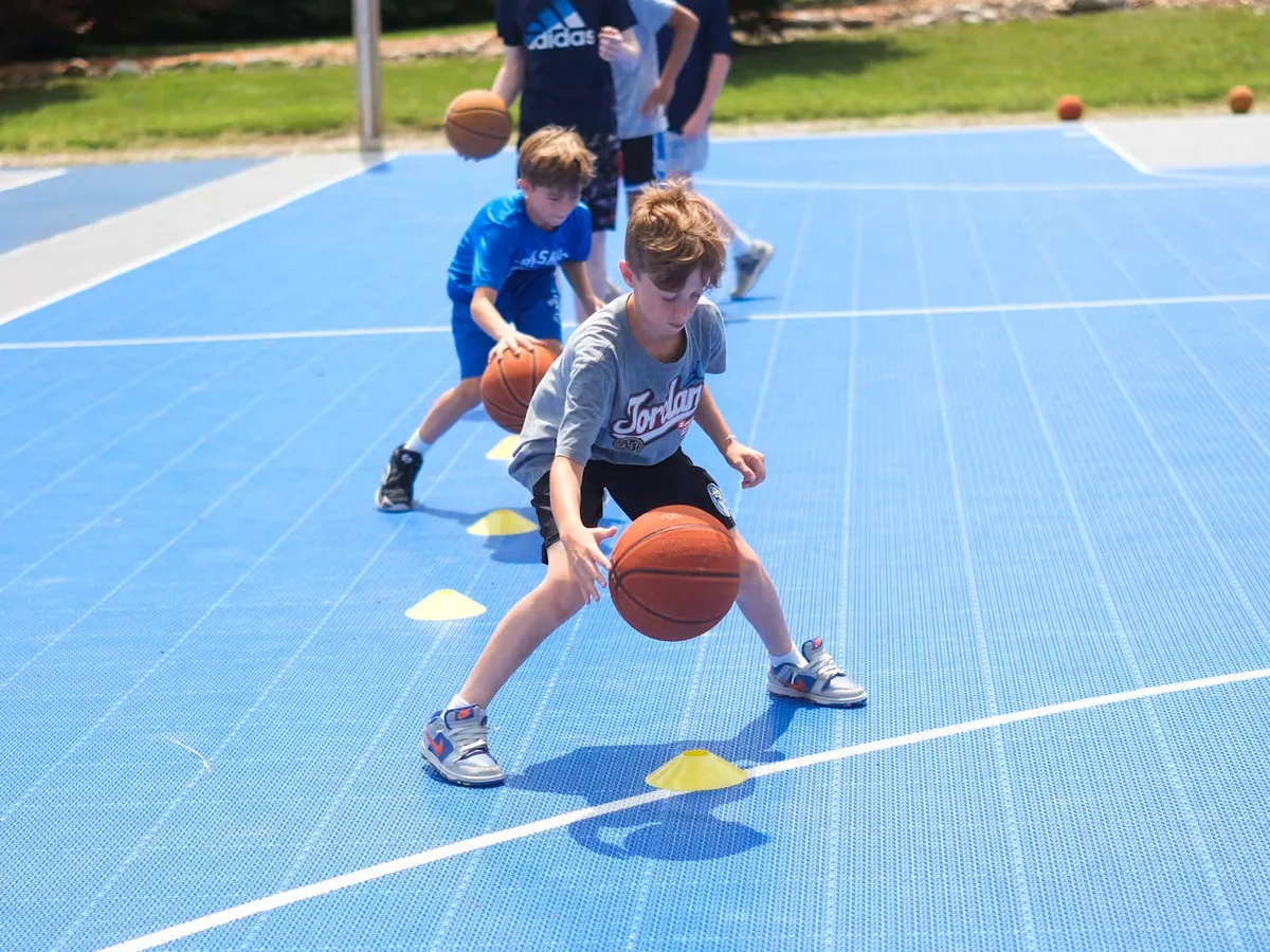 Campers dribbling basketballs on the outdoor court at Berkshire Trails Camp